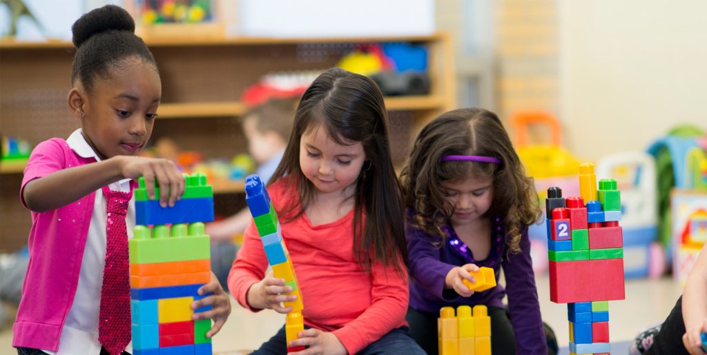 Three girls playing with blocks.