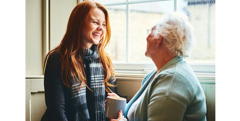 An adult and a senior adult connect over a cup of coffee