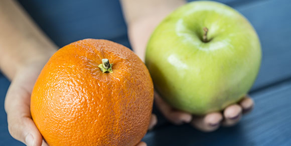 Person holding an orange and an apple.