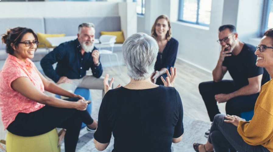 Group of people sitting in a circle chatting and laughing.