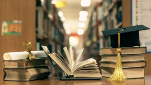 Stacks of books and a graduation mortar board.