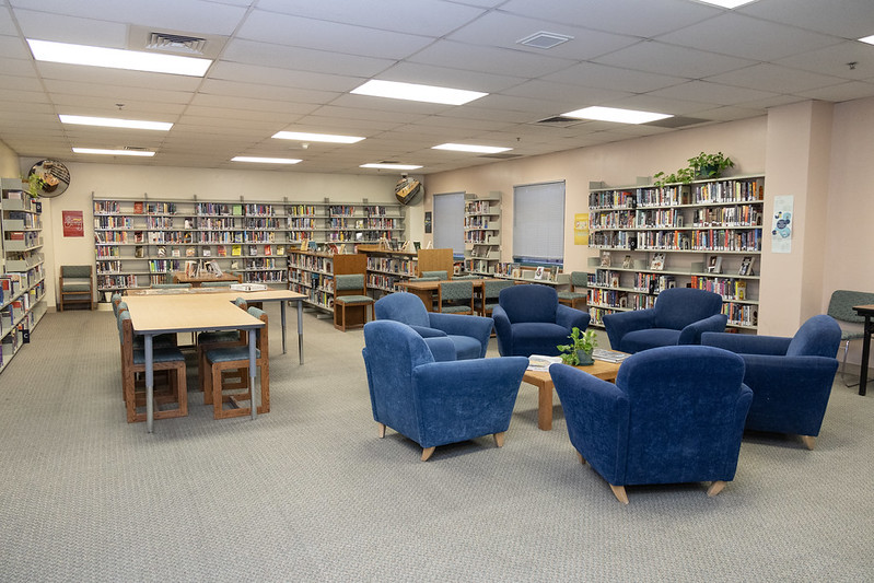 54623071588_572a4a3b70_c (2) A wide view of a prison library with blue comfy chairs.