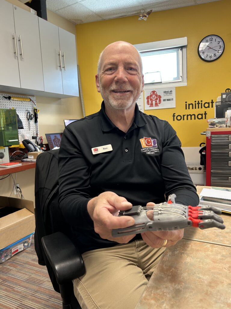 Ron holds the prosthetic child-sized hand 3D printed in the Idea Lab.
