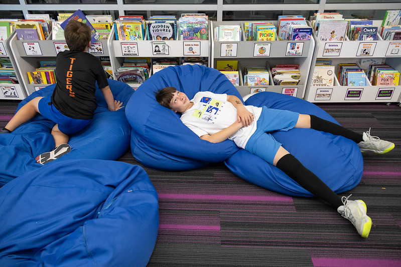 Two students lounge on beanbags and look at books.